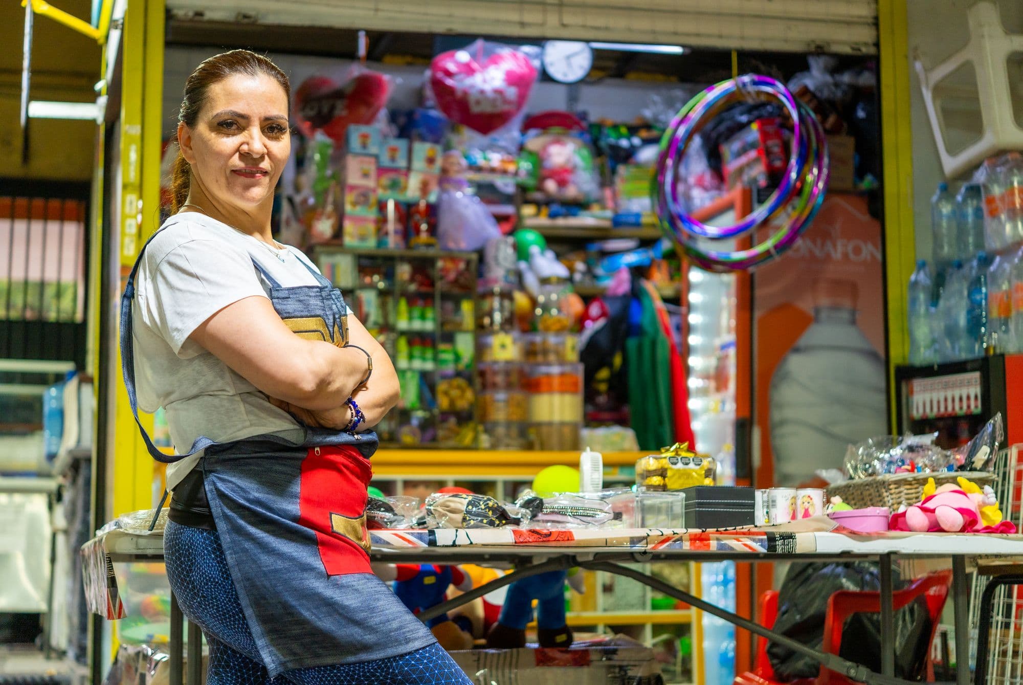 A woman proudly stands at her vibrant Mexican market stall