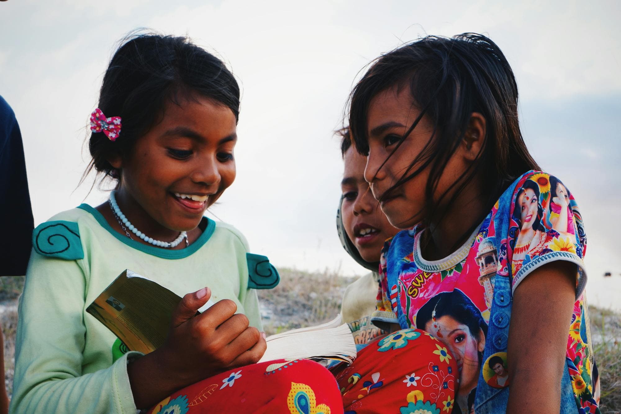 Children enjoying a book together outdoors